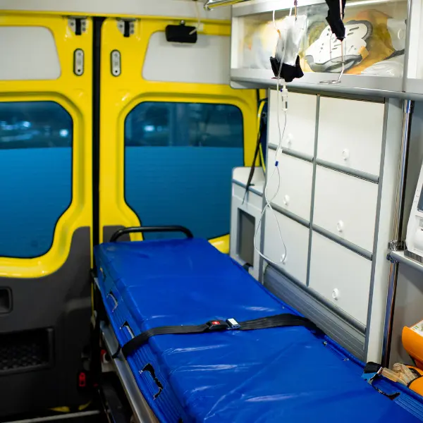 Blue transport stretcher and medical equipment inside a vehicle with yellow rear doors