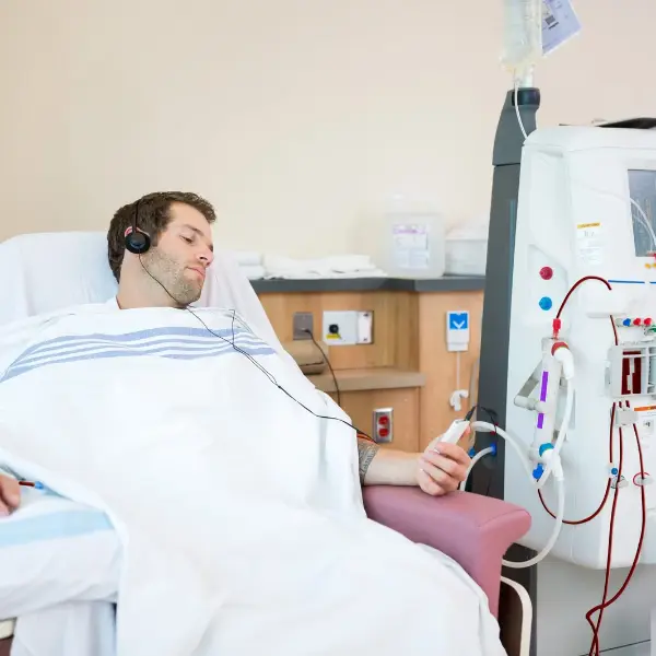 Patient receiving dialysis treatment beside a medical dialysis machine