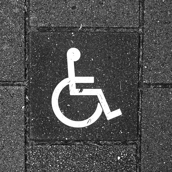White wheelchair accessibility symbol painted on dark pavement