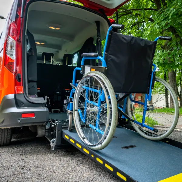 Blue manual wheelchair positioned on the access ramp of a passenger van