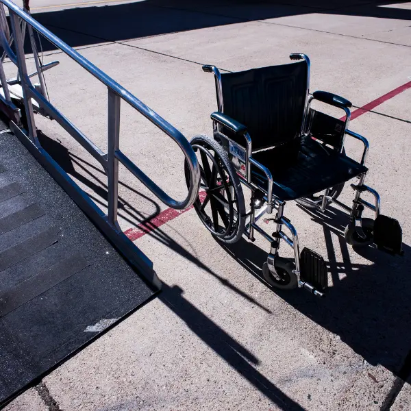 Empty manual wheelchair beside an outdoor ramp and metal handrail